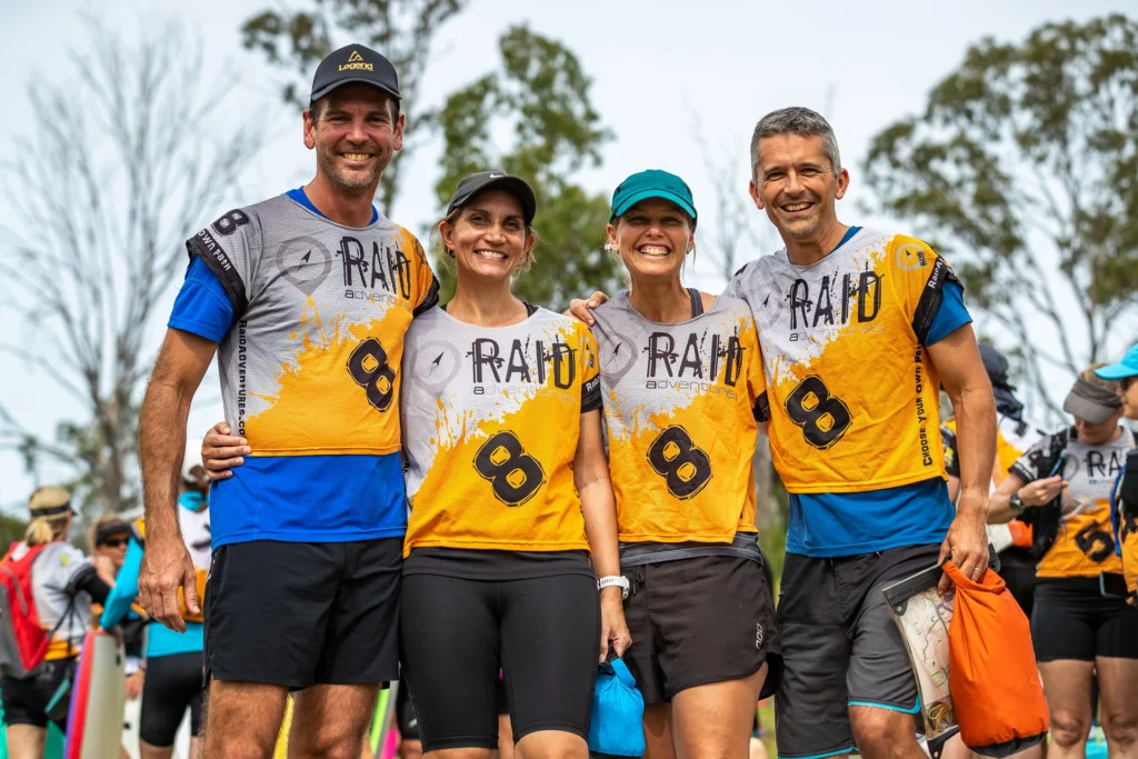 Four people in matching athletic gear pose together outdoors, smiling.