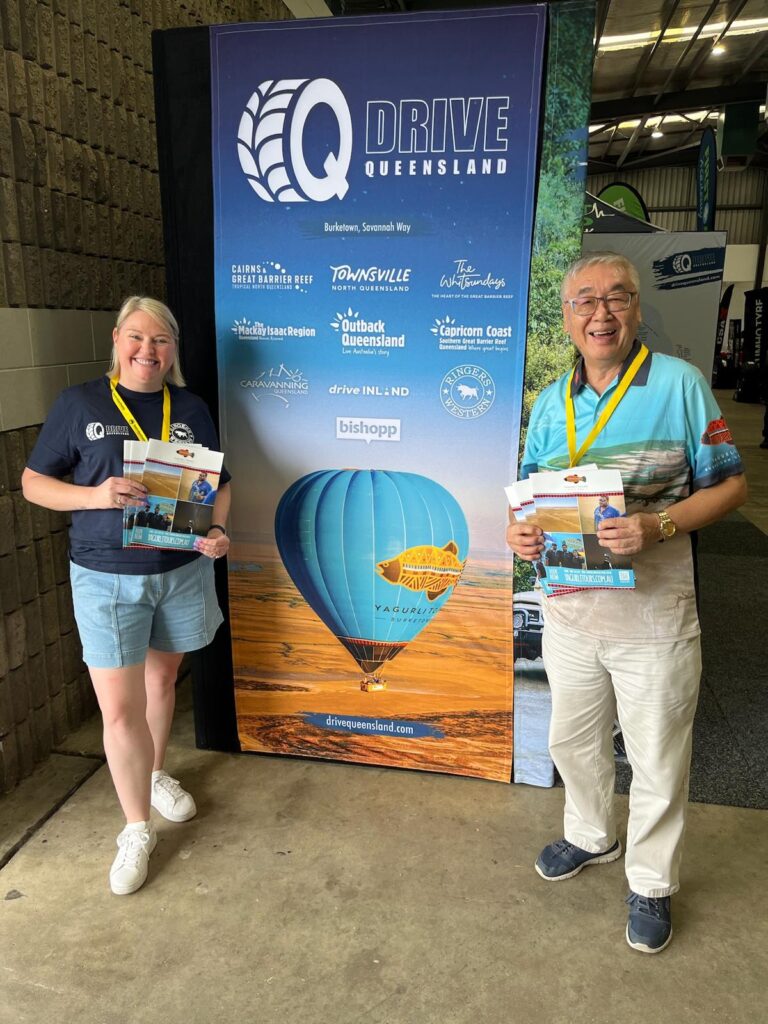 Two people stand smiling in front of a 