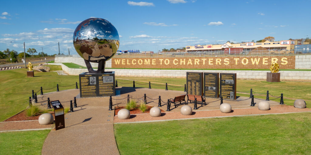 A large reflective globe sculpture with informational plaques in front of a sign reading 