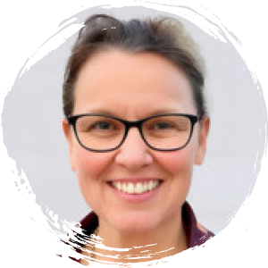 A woman with dark hair, glasses, and a checked shirt smiles at the camera against a light grey background.