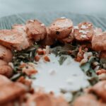 A plate with slices of biscotti arranged in a circle around a pool of white liquid, garnished with seeds and coarse salt.